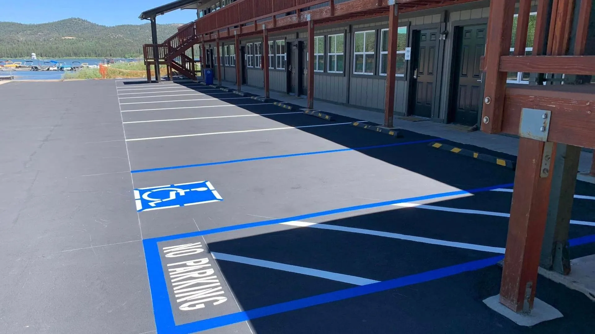 A parking lot of a motel with newly sealed asphalt and striping with an ADA spot as its focus