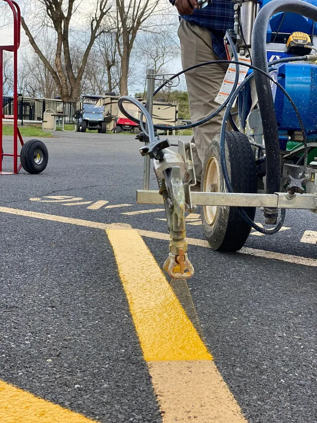 A person restriping old lines in a parking lot